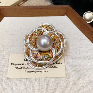 Close-up of a French style camellia brooch with tweed fabric and a central pearl.