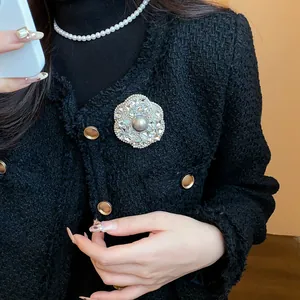 Macro view of luxury camellia brooch with crystals and gray pearl on black tweed jacket