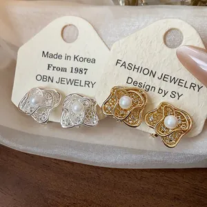 Detailed close-up of 18k gold-plated flower clip-on earrings featuring elegant white pearls.