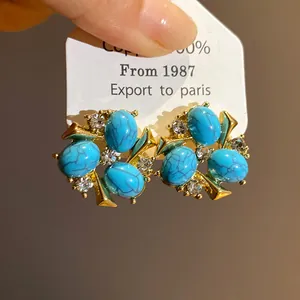 Orecchini vintage dorati con resina turchese blu e pietre di zircone scintillanti.