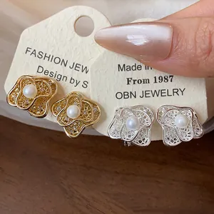 Close-up of elegant flower-shaped pearl clip-on earrings in gold and silver finishes