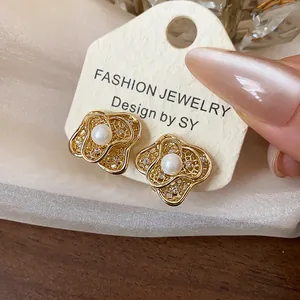 Detailed view of 18k gold plated flower shaped clip-on earrings with elegant pearl center