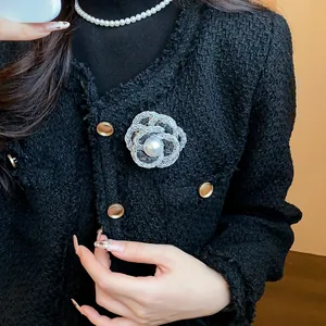 Detail view of elegant camellia brooch with pearl on a black tweed jacket for women.
