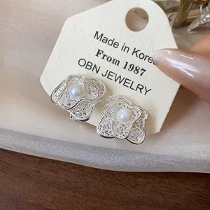 Detailed macro view of silver-plated flower clip-on earrings featuring elegant central pearls
