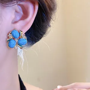 Primo piano di orecchini vintage in zircone e resina blu sull'orecchio del modello