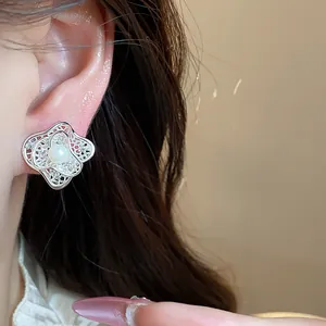 Close-up showing the elegant flower-shaped silver ear clip with pearl on model's ear