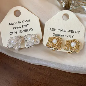 Macro view showing the intricate hollow flower design of these pearl ear clips for women
