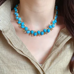 Collana vintage placcata oro con resina turchese e pietre di zircone indossata da una modella