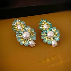 Gros plan de boucles d'oreilles fleurs avec cristaux bleus et perles blanches