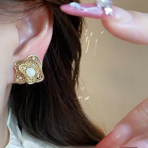 Macro view of an elegant 18k gold flower shaped ear clip featuring a central pearl detail
