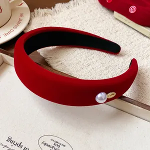 Detailed view of a red velvet wide headband with a pearl and golden accent for hair styling.