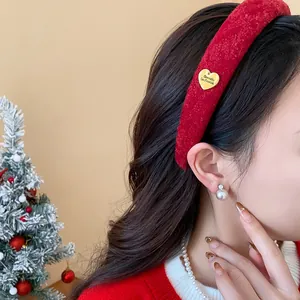 Detail of red velvet padded headband with golden heart charm on model during Christmas