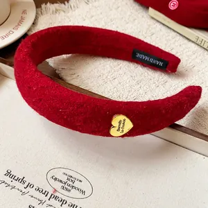 Detailed view of a red flocked headband with a gold heart charm and handmade label