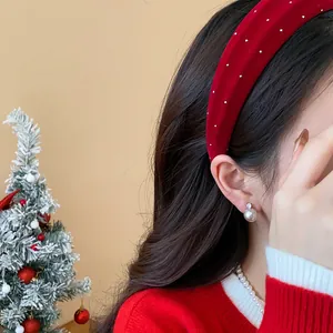 Close-up of a festive red velvet headband with studs and pearl earring on a model