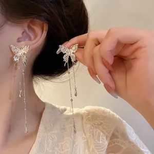 Detail view of elegant butterfly tassel earrings with long chain drapes on a model.