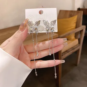 Close-up detail of silver pleated butterfly tassel earrings with sparkling rhinestone accents.