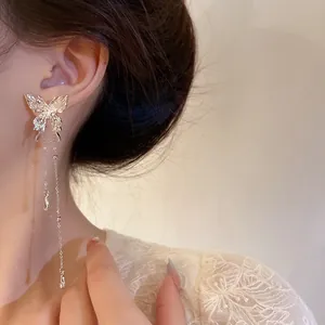Detailed view of the textured metallic butterfly and dangling chain of these earrings