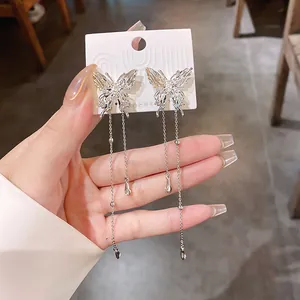 Close-up detail of silver pleated butterfly earrings featuring long elegant chain tassels