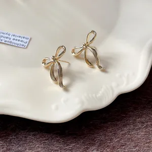 Primo piano di eleganti orecchini a lobo a forma di fiocco dorato su un piatto decorativo