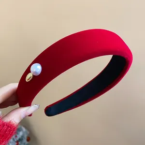 Detailed view of red velvet wide headband with pearl accent and golden charm for women