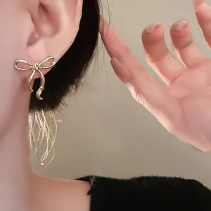 Dettaglio ravvicinato di un elegante orecchino a fiocco dorato indossato da modella