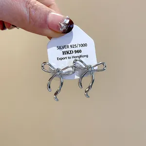 Dettaglio orecchini a lobo a fiocco in argento con marchio 925 sterling su cartoncino