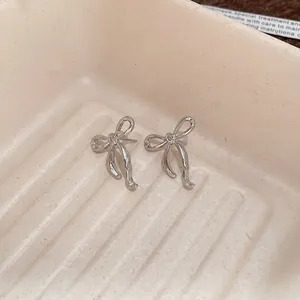 Primo piano di eleganti orecchini a lobo a fiocco argento con texture minimalista.