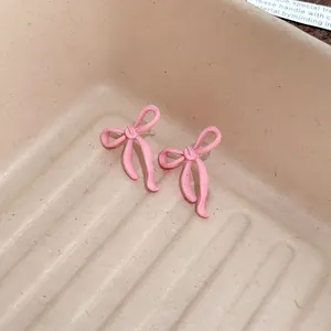 Dettaglio ravvicinato di orecchini a fiocco rosa verniciati in un vassoio minimal.