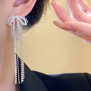 Close-up detail of elegant silver needle zircon bowknot tassel earrings worn by a model