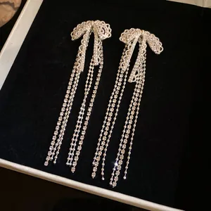 Detailed view of silver bow tassel earrings with sparkling zircons on black velvet