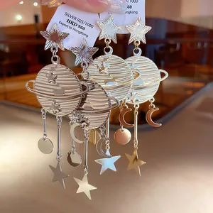 Gros plan de boucles d'oreilles planète étoile et lune avec aiguille en argent
