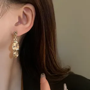 Detailed view of elegant champagne teardrop crystal earrings worn on a model's ear
