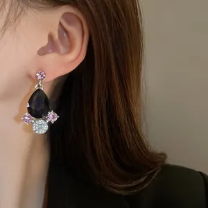 Detail close-up of retro vintage black teardrop earring with pink crystal accents on model