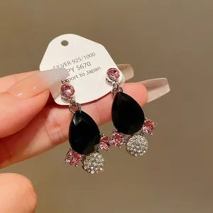Detailed macro view of retro drop-shaped earrings with black stones and pink rhinestones