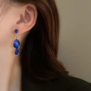 Close-up of elegant vintage-style blue waterdrop rhinestone earrings on a model