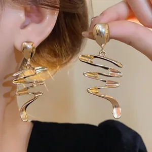 Détail de boucles d'oreilles spirales dorées montrant la texture du métal