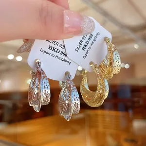 Vue détaillée de boucles d'oreilles créoles géométriques texturées en or et argent