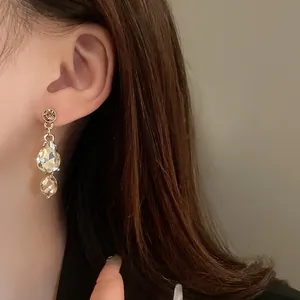 Macro detail of elegant vintage gold-toned teardrop crystal dangle earrings on model