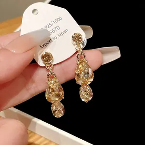 Close-up detail of elegant vintage gold earrings featuring amber waterdrop crystals