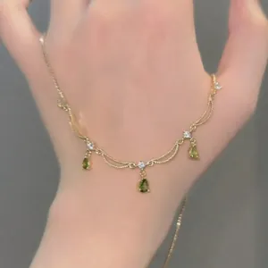 Vue détaillée d'un collier plaqué or 18 carats orné de pendentifs en zircon vert poire.