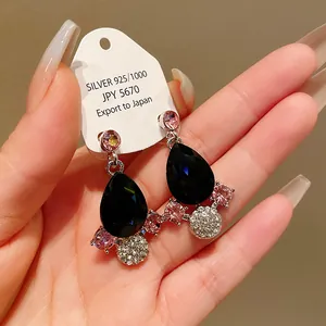 Macro view of black teardrop earrings featuring pink crystal accents in vintage style