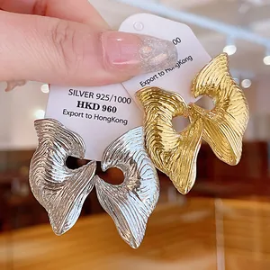 Gros plan de boucles d'oreilles géométriques texturées avec finition argentée et dorée.