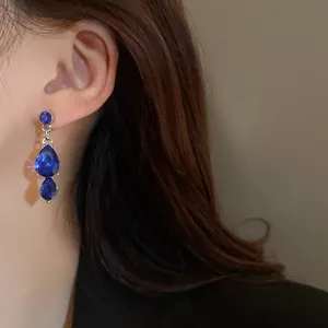 Detailed close-up of elegant vintage-style blue water-drop crystal earrings on ear