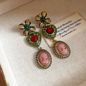 Detail shot of elegant vintage gold floral heart earrings with a pink cameo drop