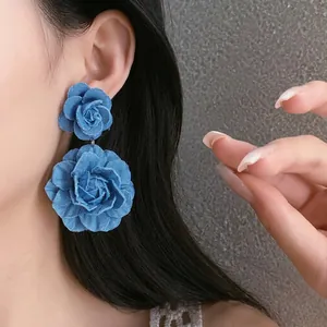 Statement blue denim fabric flower drop earrings for women worn by a model with long hair