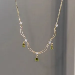 Détail du collier plaqué or 18 carats avec pendentifs en zircone verte en forme de goutte d'eau.