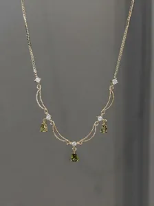 Vue détaillée d'un collier plaqué or 18 carats avec des pendentifs gouttes vertes