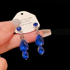 Close-up of elegant teardrop blue crystal earrings with silver setting on display