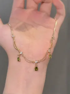 Détail d'un collier plaqué or 18k avec des pendentifs gouttes en zircon vert