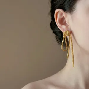 Detailed close-up of gold metal chain tassel earrings with a stylish knot design